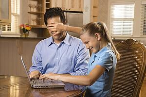 Girl covering Father's eyes.