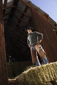 Attractive Young Man Standing on a Bale of Hay