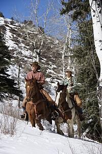 Man and Woman Riding Horses in the Snow