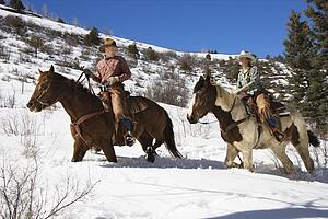 Man and Woman Riding Horses in the Snow