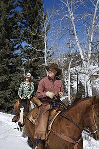 Man and Woman Riding Horses in the Snow