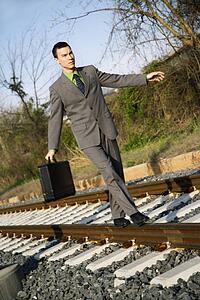 Businessman Walking on Railroad Tracks