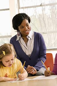Teacher Smiling and Helping Students With Schoolwork 