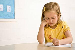 Young Girl in Classroom Writing on Paper