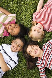 Children Lying in Clover With Heads Together