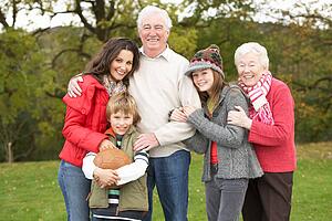 Grandparents With Grandchildren And Mother Holding Football Outside
