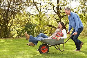 Couple With Man Giving Woman Ride In Wheelbarrow