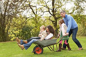 Family With Man Giving Mother And Children Ride In Wheelbarrow