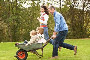 Parents Giving Children Ride In Wheelbarrow