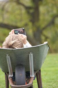 Young Boy Laying Wheelbarrow Using Smart Mobile Phone