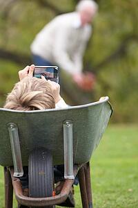 Young Boy Laying Wheelbarrow Using Smart Mobile Phone