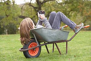 Young Girl Laying Wheelbarrow Using Smart Mobile Phone