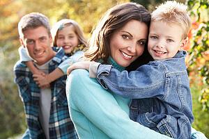 Family Group Outdoors In Autumn Landscape With Parents Giving Chiildren Piggyback