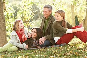 Family Group Relaxing Outdoors In Autumn Landscape