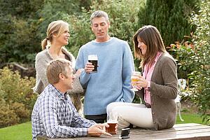 Group Of Friends Outdoors Enjoying Drink In Pub Garden