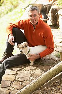 Man Outdoors With Dog Whilst On Break From Gardening
