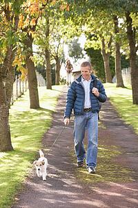 Man Walking Dog Outdoors In Autumn Park