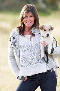 Young Woman Outdoors In Autumn Landscape Holding Dog