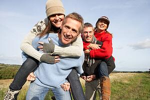 Two Couples Having Piggyback Ride In Autumn Landscape