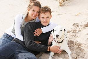 Portrait Of Romantic Teenage Couple On Beach With Dog
