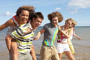 Group Of Young Friends Walking Along Summer Shoreline