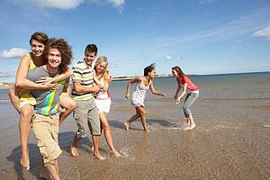 Group Of Young Friends Walking Along Summer Shoreline