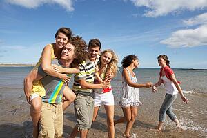 Group Of Young Friends Walking Along Summer Shoreline