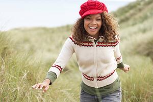 Teenage Girl Walking Through Sand Dunes Wearing Warm Clothing