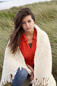 Young Woman Standing In Sand Dunes Wrapped In Blanket