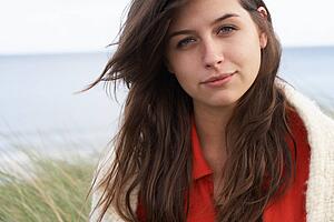 Young Woman Standing In Sand Dunes Wrapped In Blanket