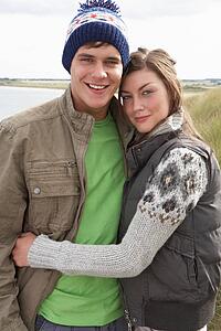 Young Couple Walking Through Sand Dunes Wearing Warm Clothing