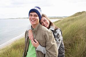 Young Couple Walking Through Sand Dunes Wearing Warm Clothing
