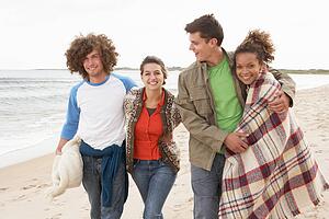 Group Of Young Friends Walking Along Autumn Shoreline
