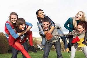 Group Of Teenage Friends Having Piggyback Rides In Autumn Landscape