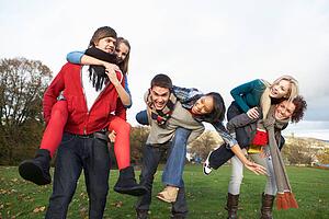 Group Of Teenage Friends Having Piggyback Rides In Autumn Landscape
