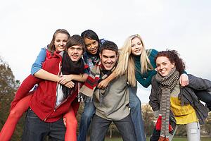 Group Of Teenage Friends Having Piggyback Rides In Autumn Landscape