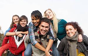 Group Of Teenage Friends Having Piggyback Rides In Autumn Landscape