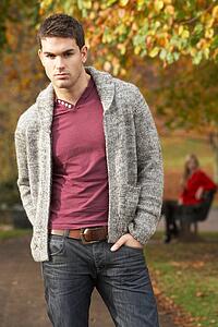 Teenage Boy Standing In Autumn Park With Female Figure On Bench In Background