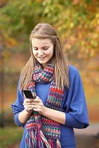 Teenage Girl Making Mobile Phone Call In Autumn Landscape