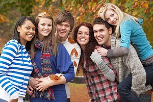 Group Of Six Teenage Friends Having Fun In Autumn Park