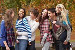 Group Of Six Teenage Friends Having Fun In Autumn Park