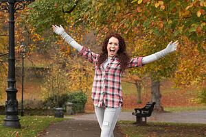 Teenage Girl Standing In Autumn Park With Arms Outstretched