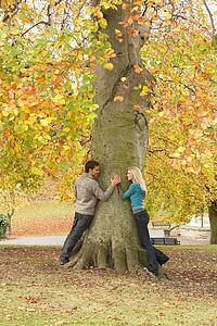Romantic Teenage Couple By Tree In Autumn Park