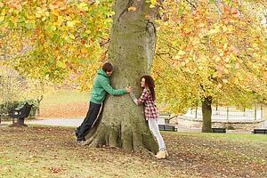 Romantic Teenage Couple By Tree In Autumn Park