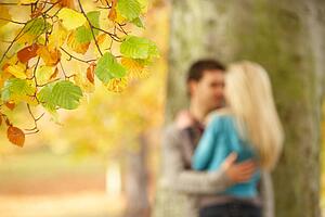 Shallow Focus View Of Romantic Teenage Couple By Tree In Autumn Park