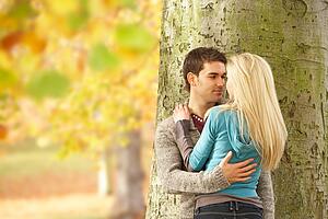 Romantic Teenage Couple By Tree In Autumn Park
