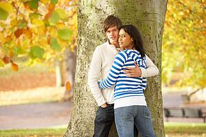 Romantic Teenage Couple By Tree In Autumn Park
