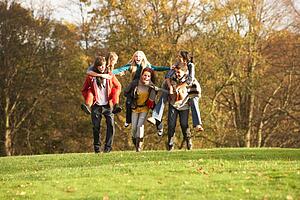 Group Of Teenage Friends Having Piggyback Rides In Autumn Landscape