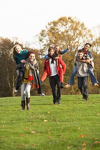 Group Of Teenage Friends Having Piggyback Rides In Autumn Landscape