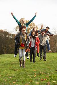 Group Of Teenage Friends Having Piggyback Rides In Autumn Landscape